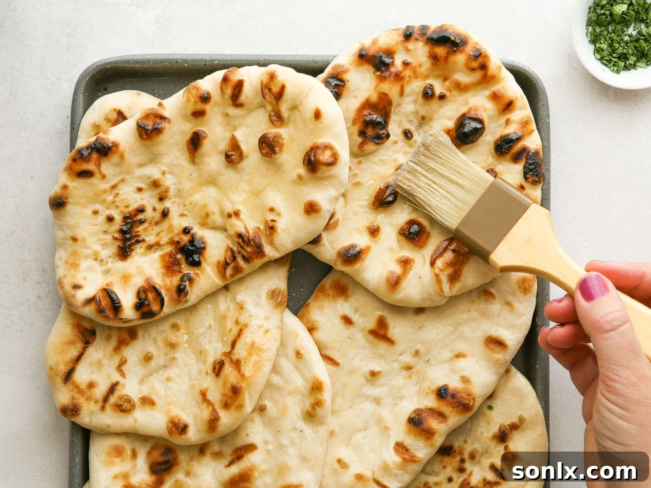 brushing freshly grilled flatbread with melted butter for added flavor and sheen