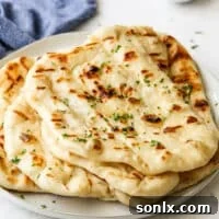 grilled flatbread stacked on a plate, garnished with fresh herbs