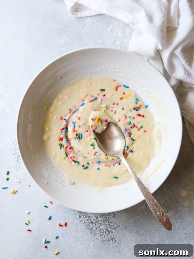 Vibrant funfetti cupcake batter in a glass bowl, showcasing colorful sprinkles mixed throughout, ready to be baked into delicious treats.