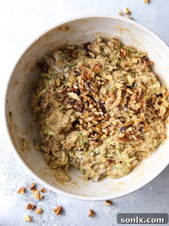 Mixing up the batter for banana zucchini walnut bread in a large bowl, showing its rich texture