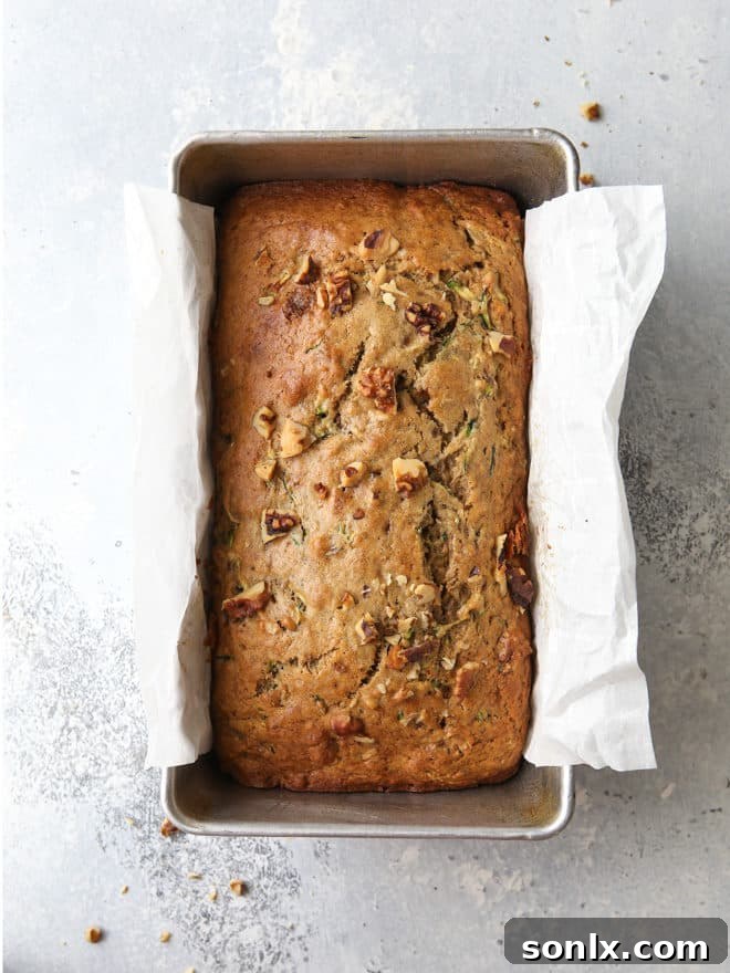Two golden brown loaves of banana zucchini walnut bread cooling on a wire rack, ready to be enjoyed