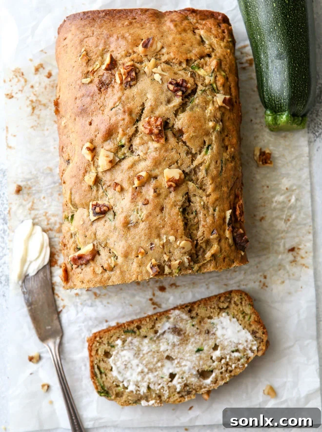A beautifully sliced loaf of banana zucchini walnut bread, showing its moist interior and scattered walnuts
