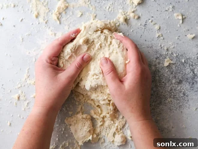 A baker forming pie crust dough into two distinct disks on a work surface, preparing them for chilling.