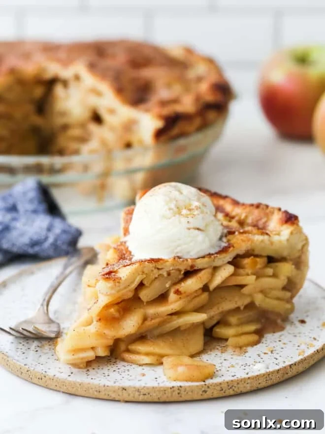 slice of mile high apple pie with a scoop of vanilla ice cream on a plate