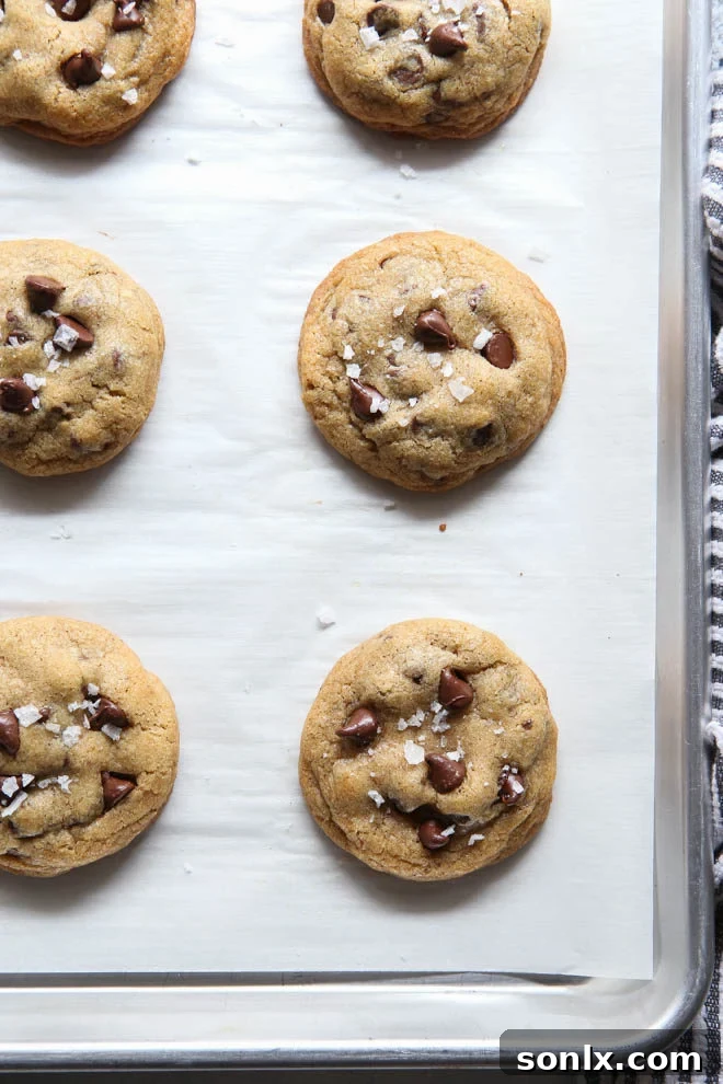 How to bake perfectly pretty cookies on completelydelicious.com. A stack of brown butter chocolate chip cookies on a cooling rack.