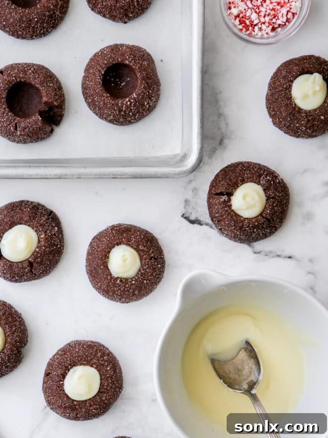 Freshly baked chocolate mint thumbprint cookies with glistening ganache filling on a cooling rack