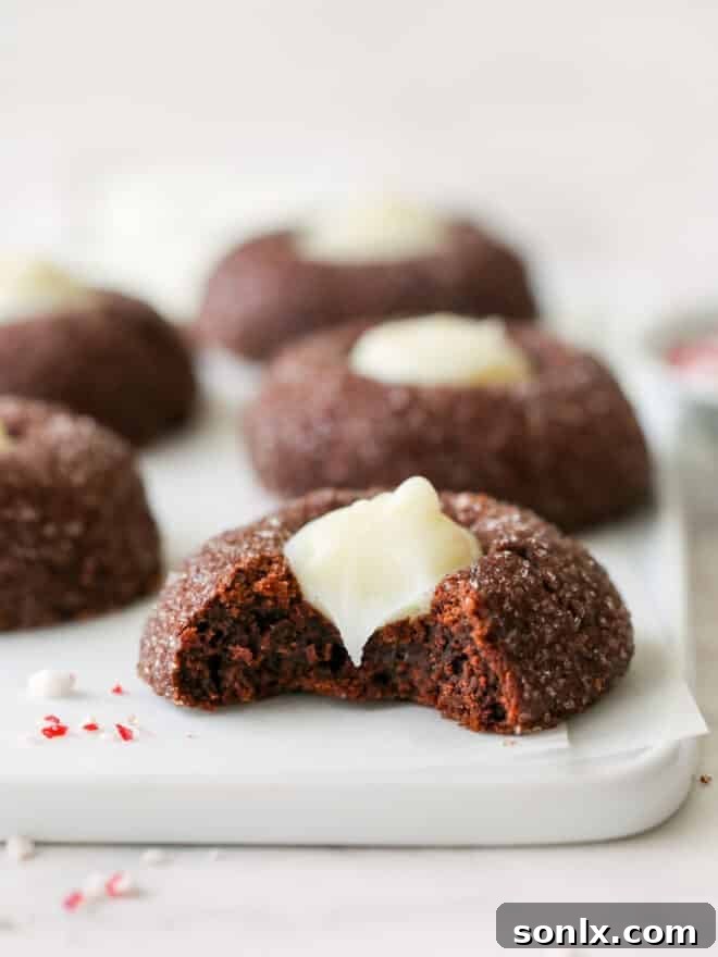 Close-up of a chocolate mint thumbprint cookie with a bite taken out, revealing the soft interior and creamy filling