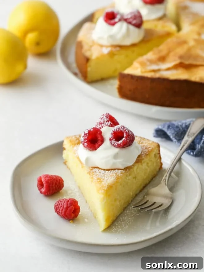 A beautifully presented slice of lemon olive oil cake on a plate, garnished with fresh berries and a light dusting of powdered sugar.