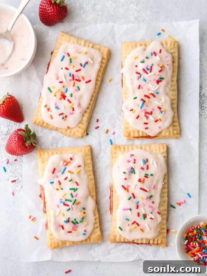 Artisan Strawberry Toaster Pastries 6 Freshly baked strawberry pop tarts with white frosting and rainbow sprinkles on a cooling rack
