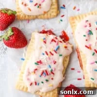 A close-up of a homemade strawberry pop tart with pink frosting and sprinkles