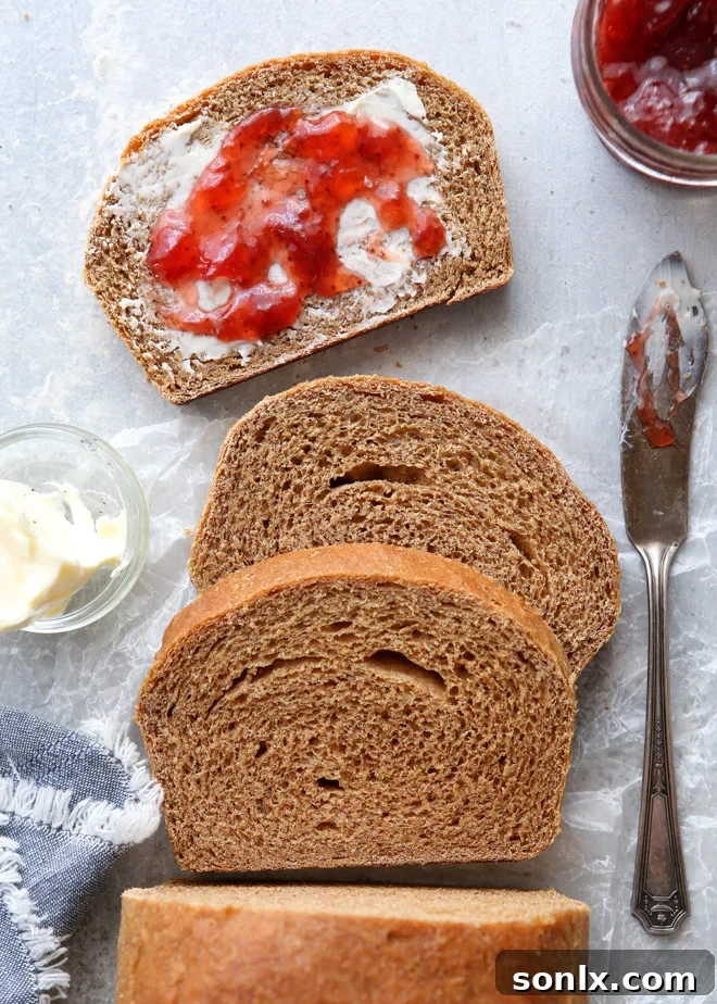 A beautifully golden-brown loaf of simple and hearty 100% whole wheat bread, freshly baked and ready to be sliced.