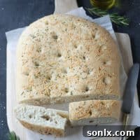 Delicious Rosemary and Parmesan Focaccia bread, golden brown and sprinkled with herbs and cheese.