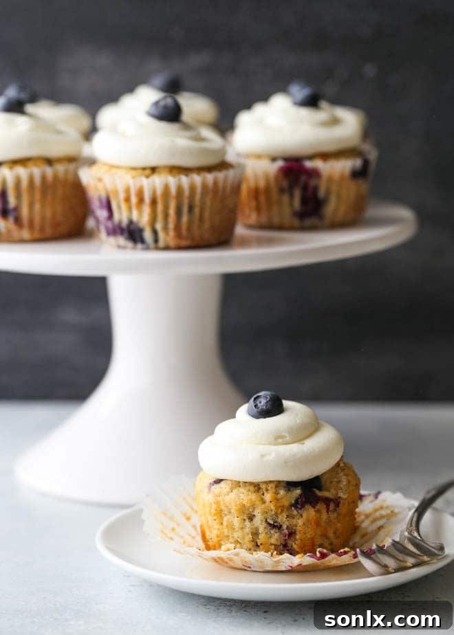 A stunning spread of blueberry muffin cupcakes with lemon cream cheese frosting, ready to be served at a brunch or party setting.