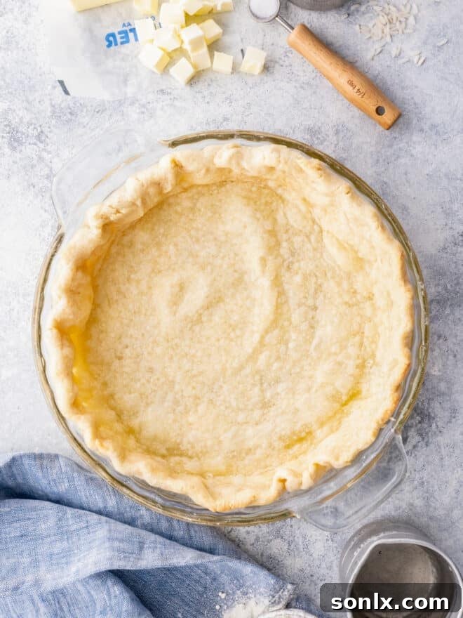 A perfectly golden, fully blind-baked pie crust resting on a linen cloth, ready for filling.
