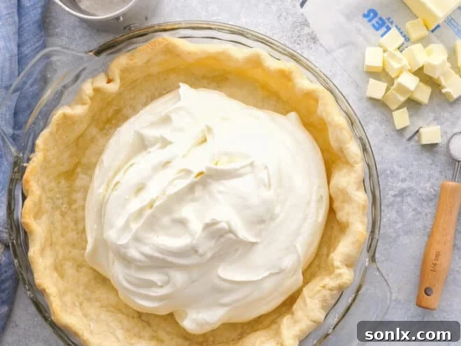 A perfectly blind-baked pie crust being filled with a creamy, rich filling, showcasing its structural integrity.