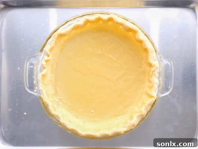 A partially blind-baked pie crust, golden at the edges, with the foil and weights just removed, ready for filling.