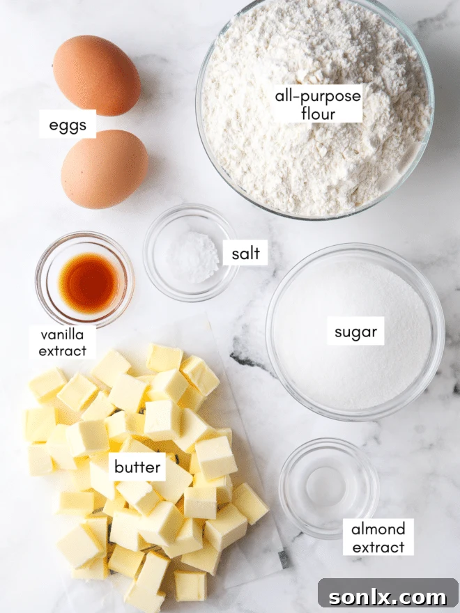 A collection of essential ingredients for spritz cookies: butter, sugar, eggs, extracts, and flour.