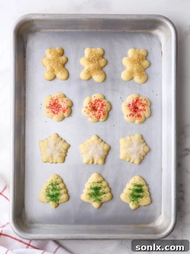 A beautiful assortment of baked spritz cookies in various festive shapes, adorned with colorful sprinkles.
