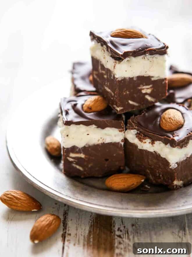 Freshly sliced coconut almond fudge squares on a wooden cutting board, showcasing the beautiful layers.