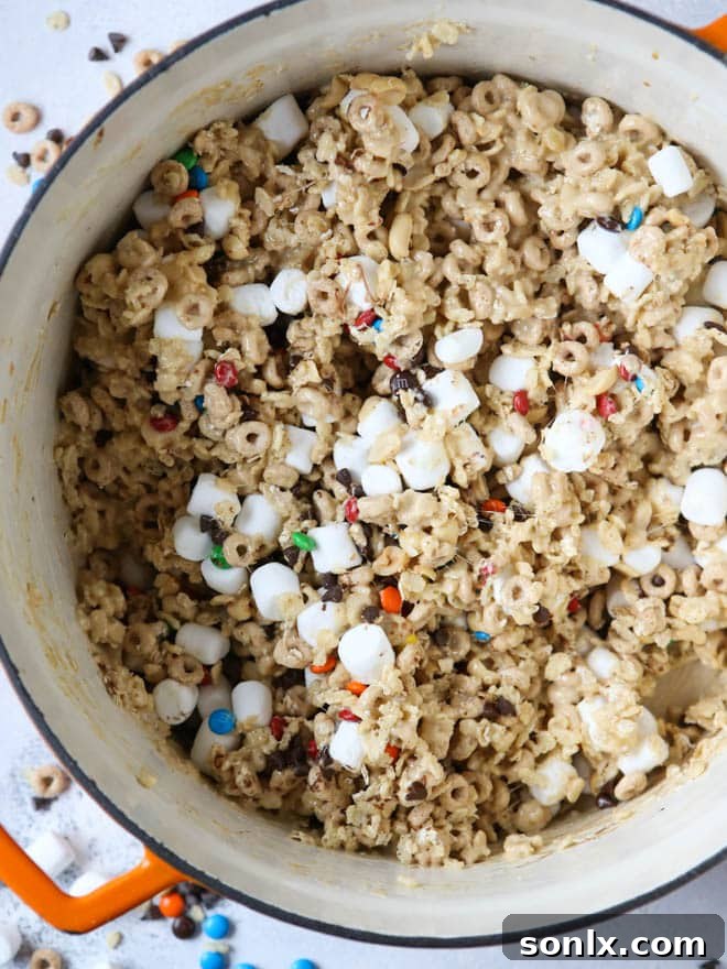 A close-up of the gooey marshmallow and cereal mixture being stirred in a large pot, ready for the mix-ins.
