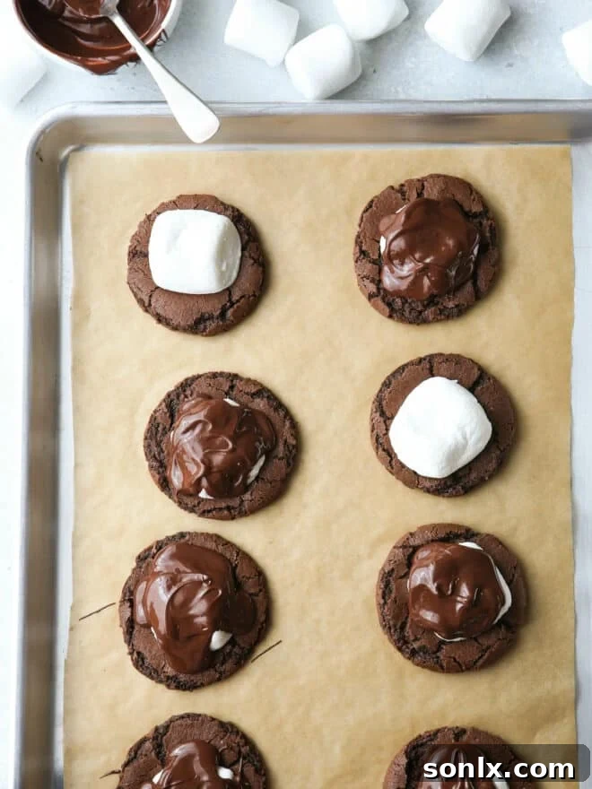 close-up of hands placing marshmallows and melted chocolate on cookies
