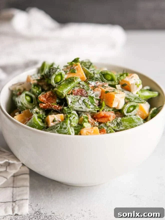 Creamy sugar snap pea salad with bacon and cheddar in a bowl, ready to be served