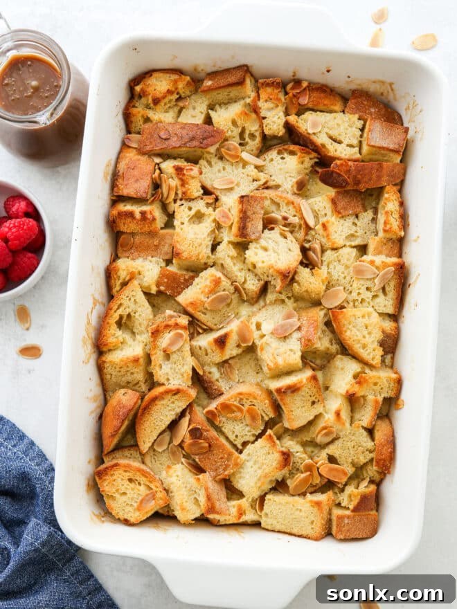 A baked almond bread pudding in a ceramic casserole dish, golden brown and ready to be served.