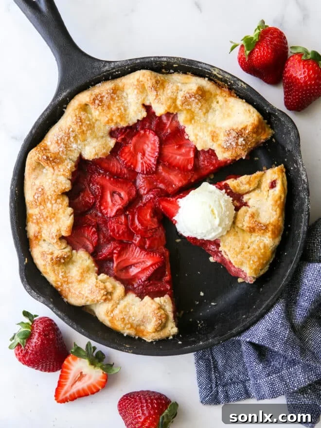 A vibrant slice of strawberry skillet pie adorned with a generous scoop of vanilla ice cream, showcasing its golden, flaky crust and bubbling fruit filling.