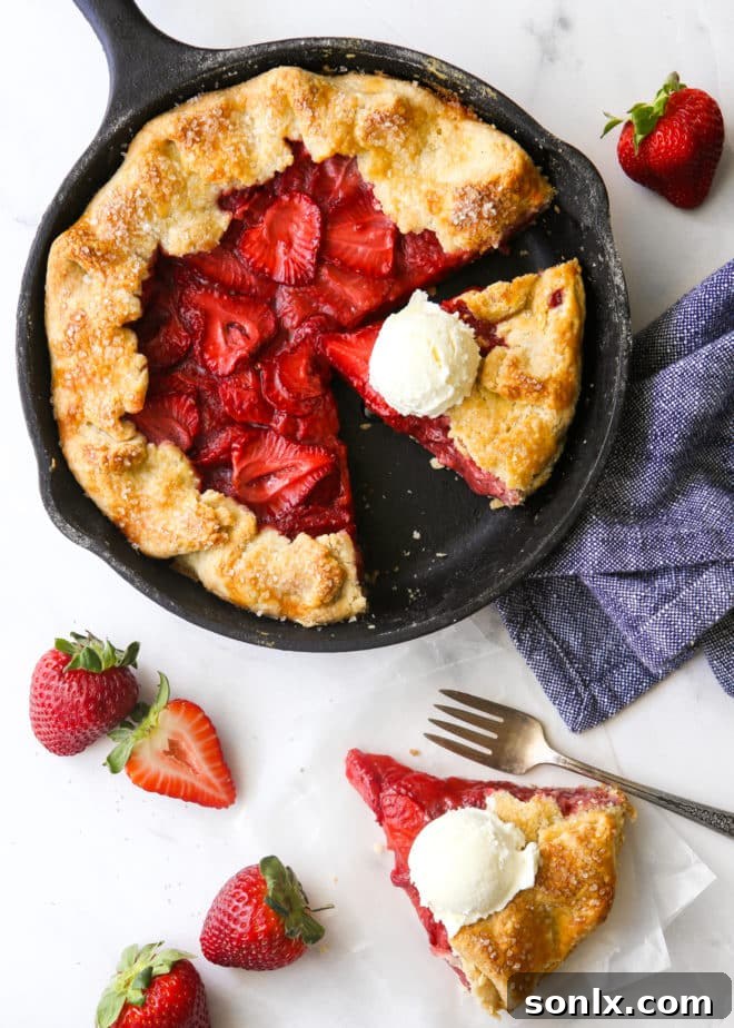 A beautifully baked strawberry skillet pie, with a single slice removed revealing the juicy filling, accompanied by generous scoops of vanilla ice cream, creating an irresistible summer dessert scene.