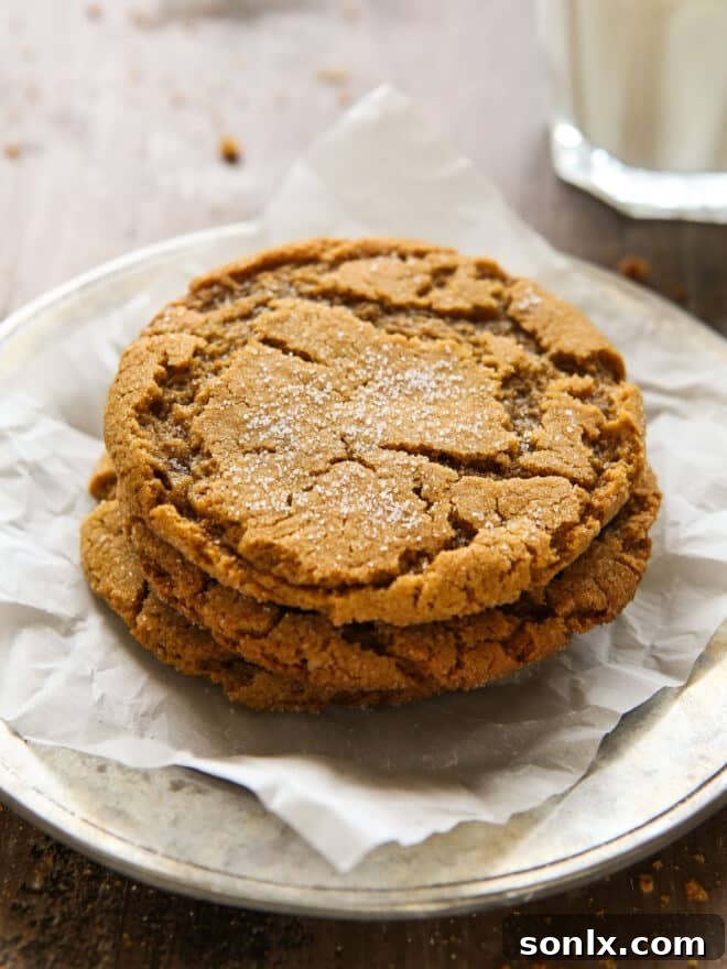 Another enticing view of a stack of chewy gingersnap cookies on a plate with a glass of milk, emphasizing their golden color and inviting texture, ready to be enjoyed.