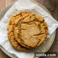 A stack of beautifully baked chewy gingersnaps on a plate with a glass of milk, invitingly presented as the star of the recipe.