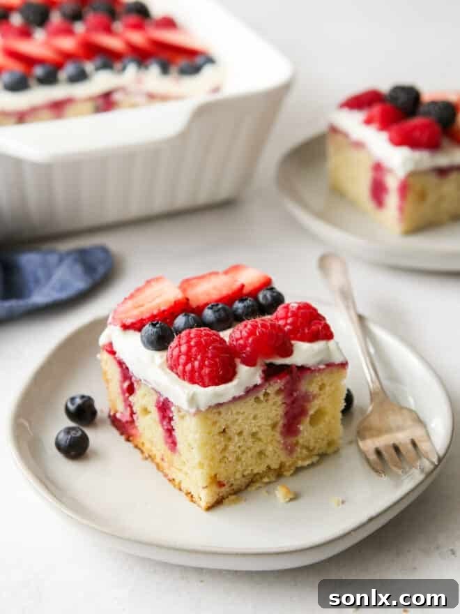 Delicious homemade berry poke cake ready to be served, topped with fresh berries