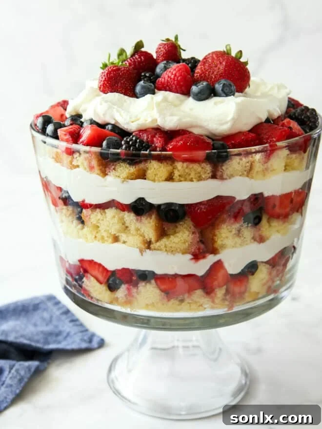 Berry trifle in a large glass trifle dish, showcasing layers of cake, cream, and berries