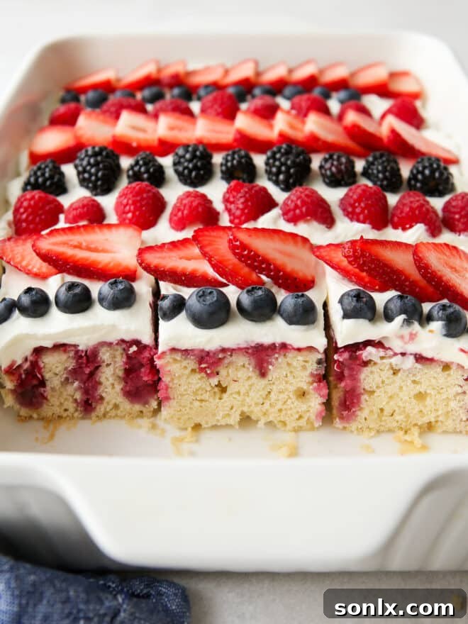 Closeup of the finished berry poke cake, showing the rich berry filling and whipped cream topping.