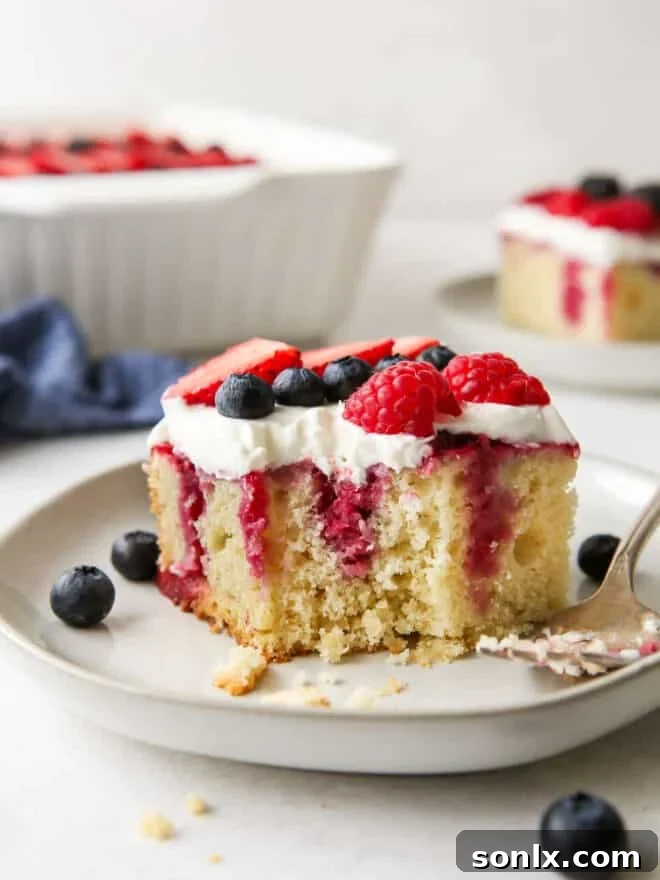 Overhead shot of the finished berry poke cake, beautifully decorated with fresh berries