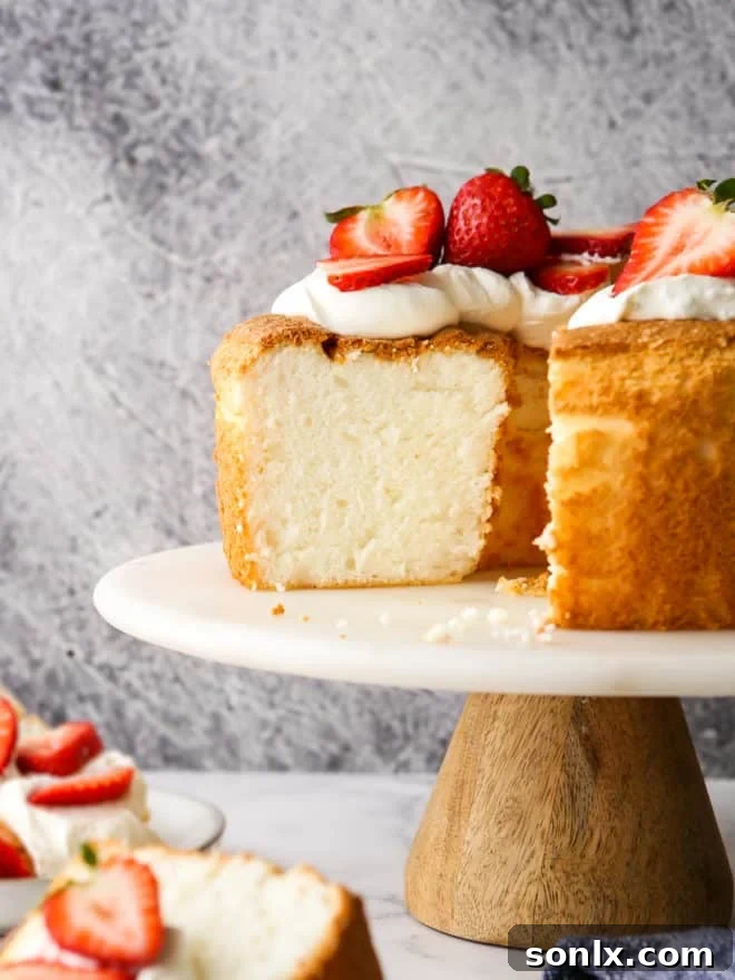 Close-up view of a perfectly baked Angel Food Cake on an elegant cake stand, showcasing its lofty height and airy texture.