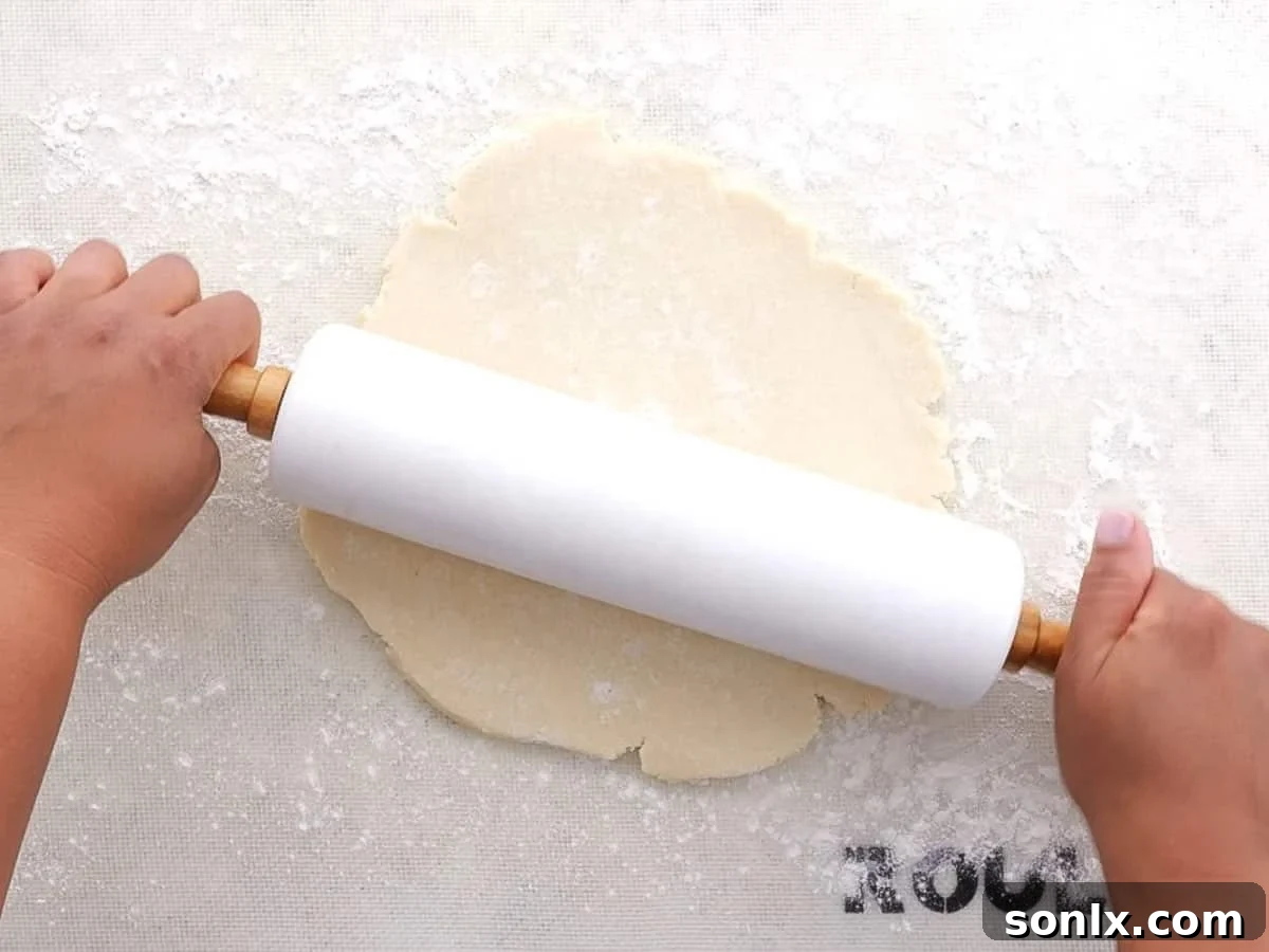 Rustic Orchard Peach Apple Galette 5 Rolling out homemade pie crust on a floured surface, preparing for galette assembly