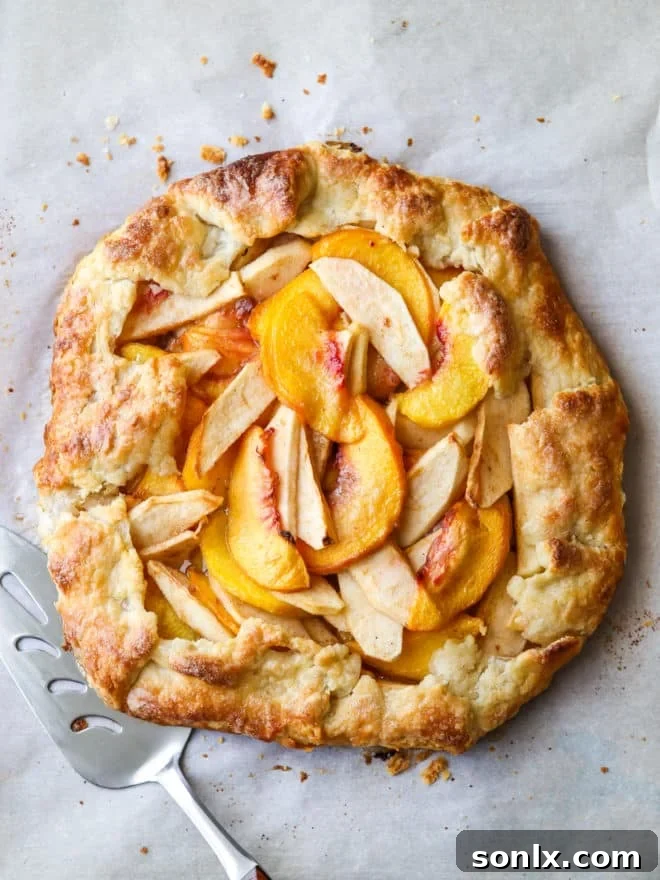Rustic Orchard Peach Apple Galette 8 Freshly baked peach apple galette on a parchment-lined baking pan, golden brown and bubbling