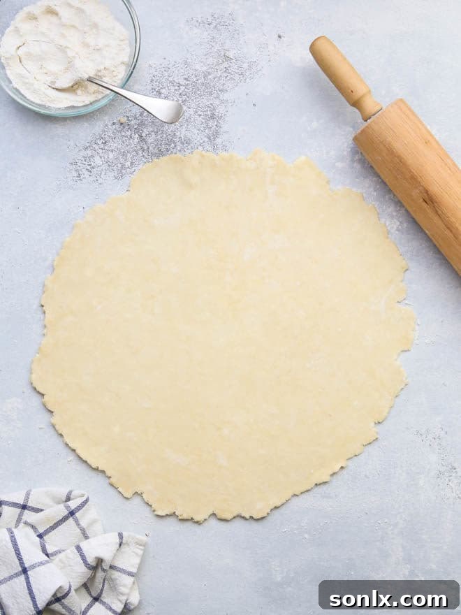 Two hands pressing together a cracked edge of pie dough, illustrating repair techniques.