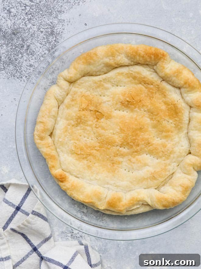 Pie crust lined with foil and pie weights, ready for blind baking to prevent shrinkage.