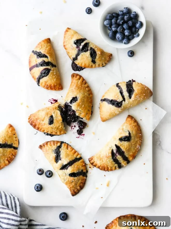 Delicious blueberry hand pies arranged on a plate, with one cut open to reveal the rich, gooey fruit filling.