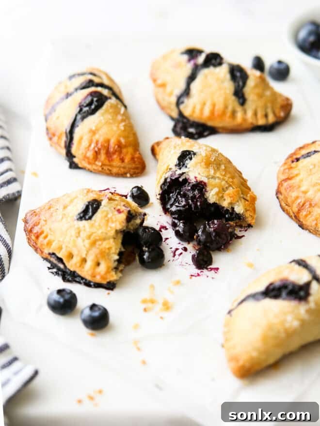 A close-up shot of a blueberry hand pie, cut open to display the luscious, glistening blueberry filling within its flaky crust.