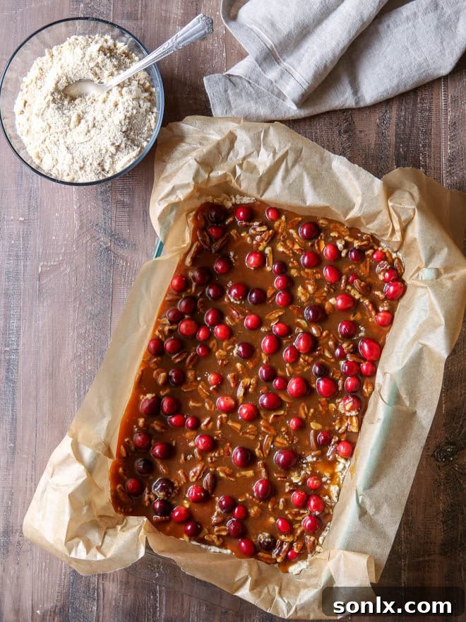 Caramel cranberry pecan nut bars ready for baking in the oven, showcasing the crumb topping.