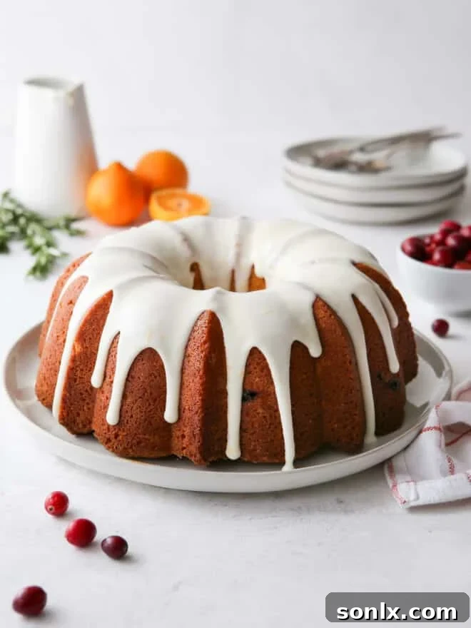 glazed cranberry orange bundt cake on a plate with festive decor