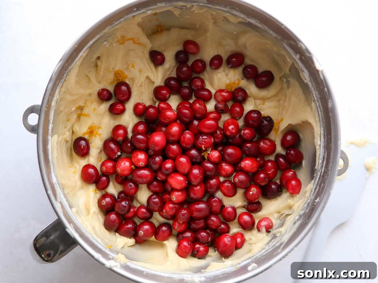 adding cranberries to bundt cake batter by hand