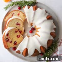 cranberry orange bundt cake and slices on a plate with orange glaze