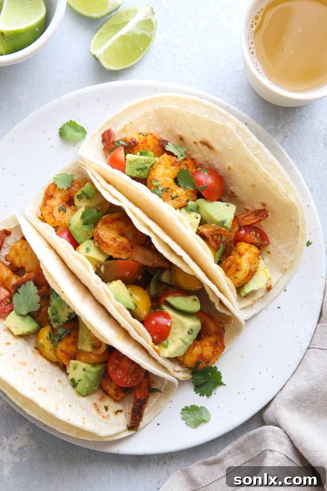 Hand holding a Mumbai Spiced Shrimp Taco, showing the generous filling of shrimp and avocado salsa