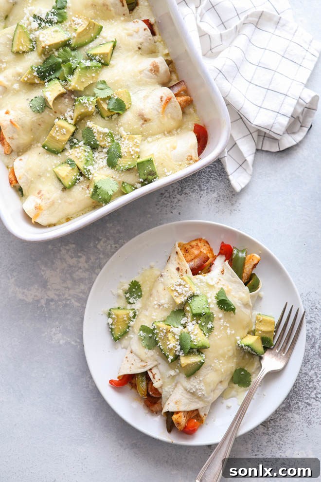 Chicken fajitas meets cheesy enchiladas in this fun main dish mashup - Golden brown chicken fajita enchiladas in a baking dish, garnished with fresh cilantro and avocado slices.