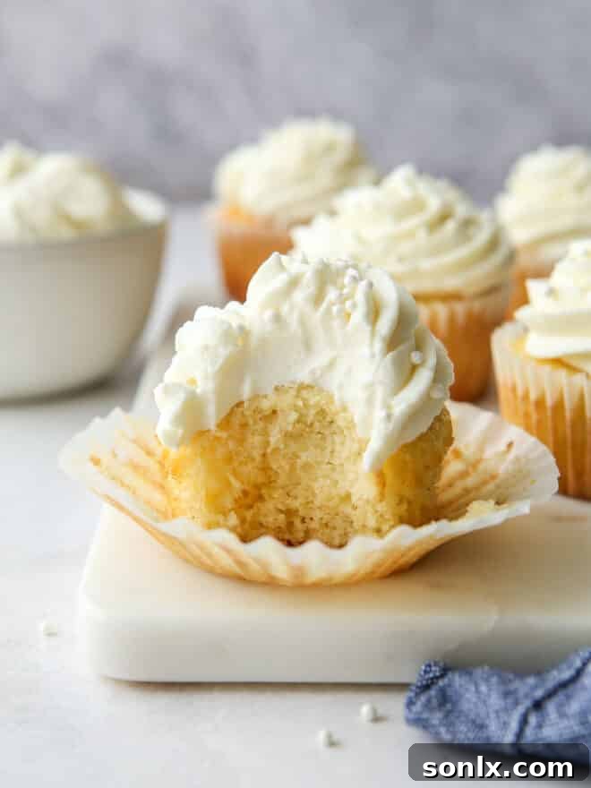 Close-up of a vanilla cupcake revealing its tender crumb and delicate texture, topped with a swirl of frosting.