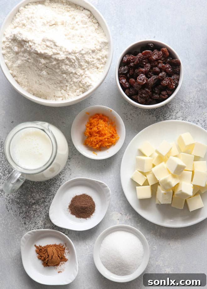 Ingredients for making homemade hot cross biscuits, including flour, butter, sugar, spices, and dried fruit laid out on a table